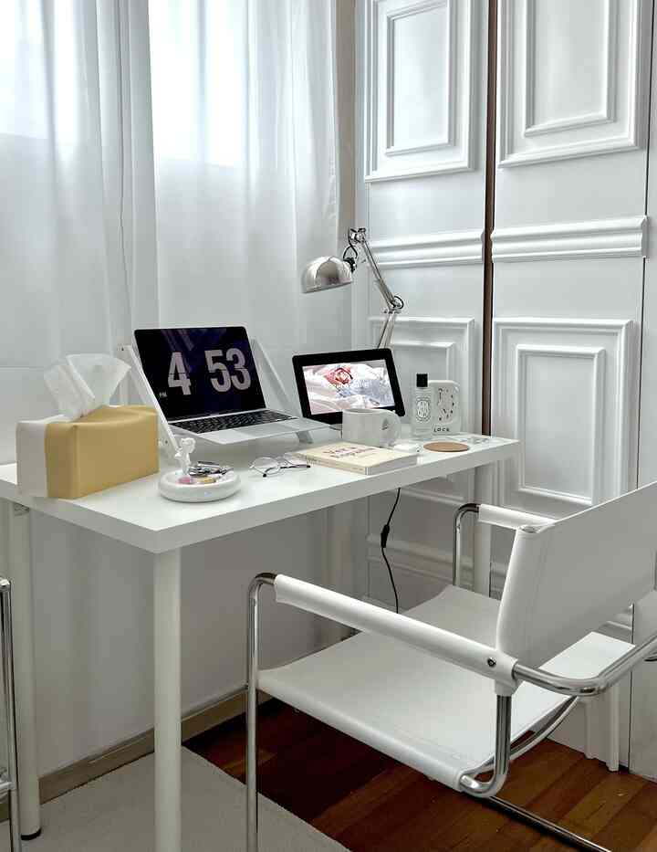 白を基調としたホームオフィス、シンプルなデスクとアームチェアが配置され、明るく清潔感のある印象的な空間