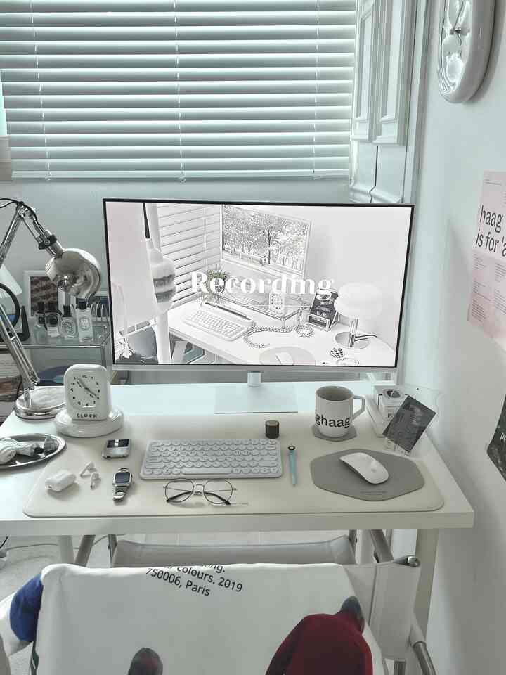 ホワイトトーンのワンルームホームオフィス、サムスンのスマートモニターとデスクランプが配置された整った作業環境