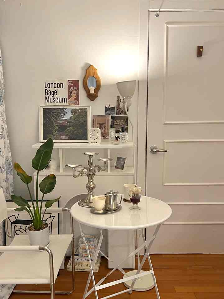 白と木目調のリビング、丸いダイニングテーブルと植物が配置されたミニマルでカフェ風の印象的な空間