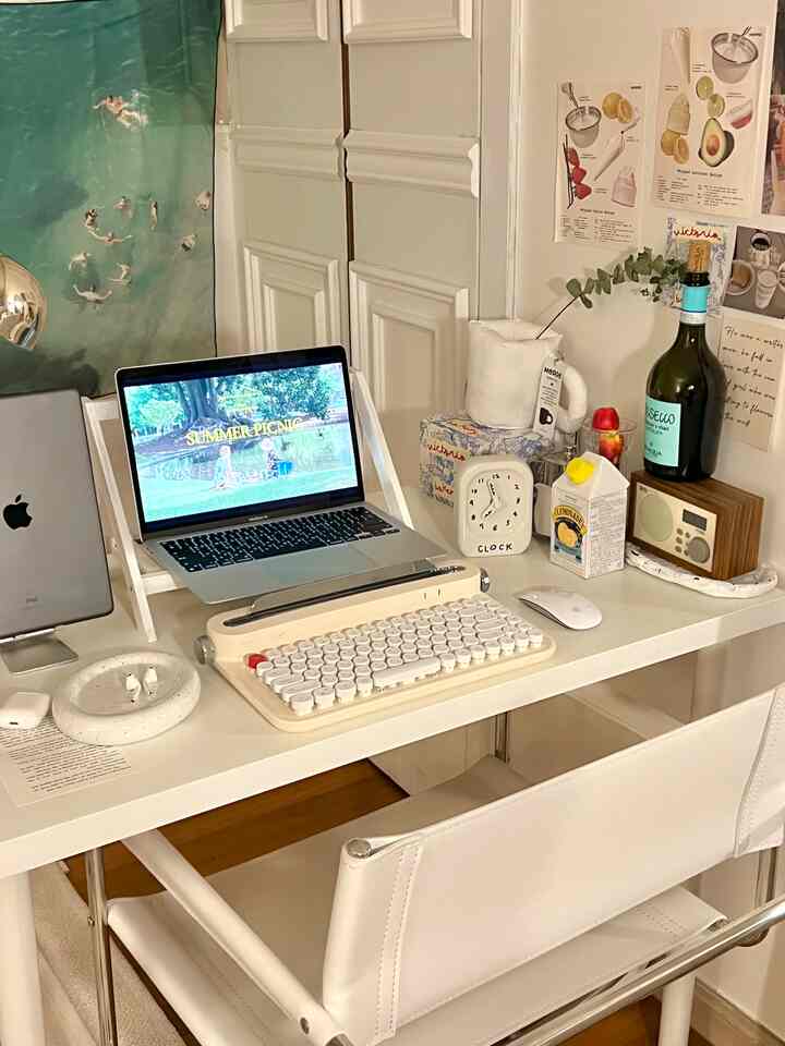白を基調としたコンパクトなホームオフィス、レトロなキーボードとノートパソコン、様々なデスクアクセサリーが配置された雰囲気のある作業空間