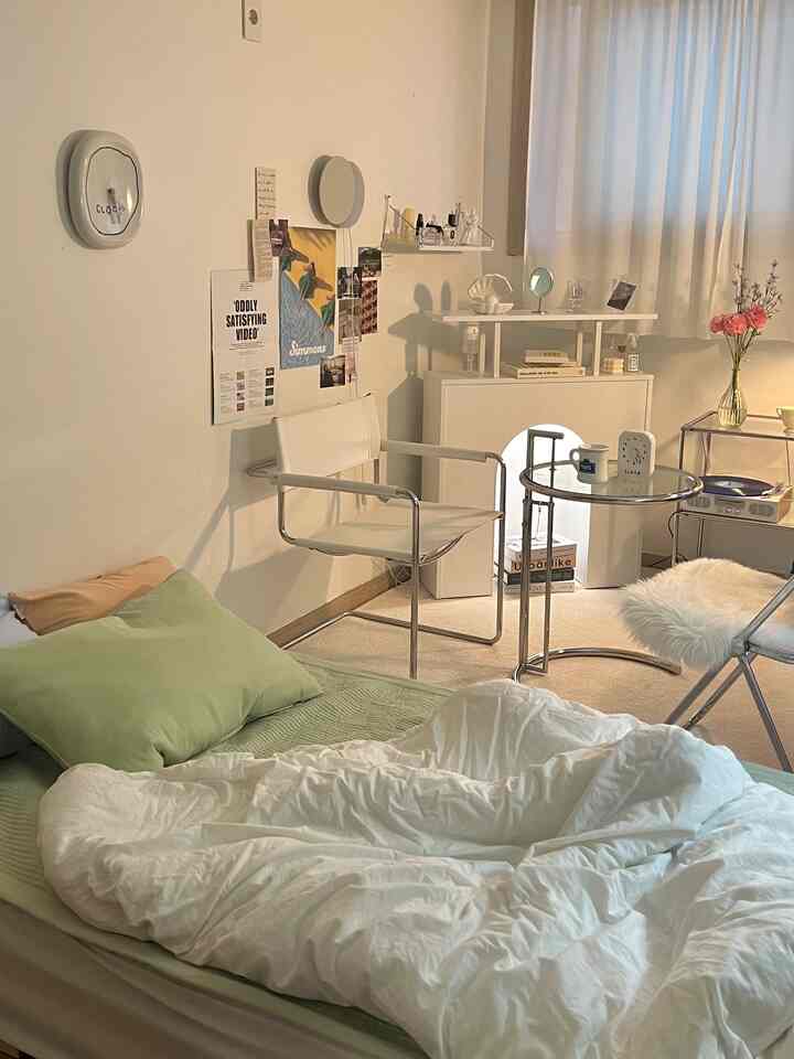 白と緑の色調の寝室、ベッドとアームチェア、サイドテーブルが配置された雰囲気のあるインテリア