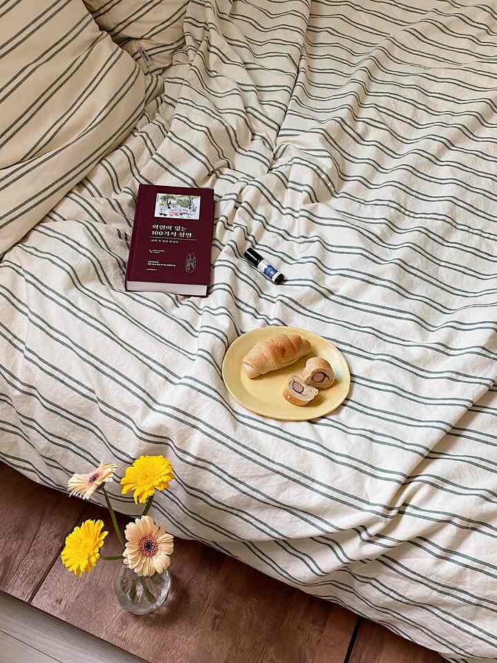 ナチュラルな木目調とベージュのストライプ寝具が配置された落ち着いた寝室