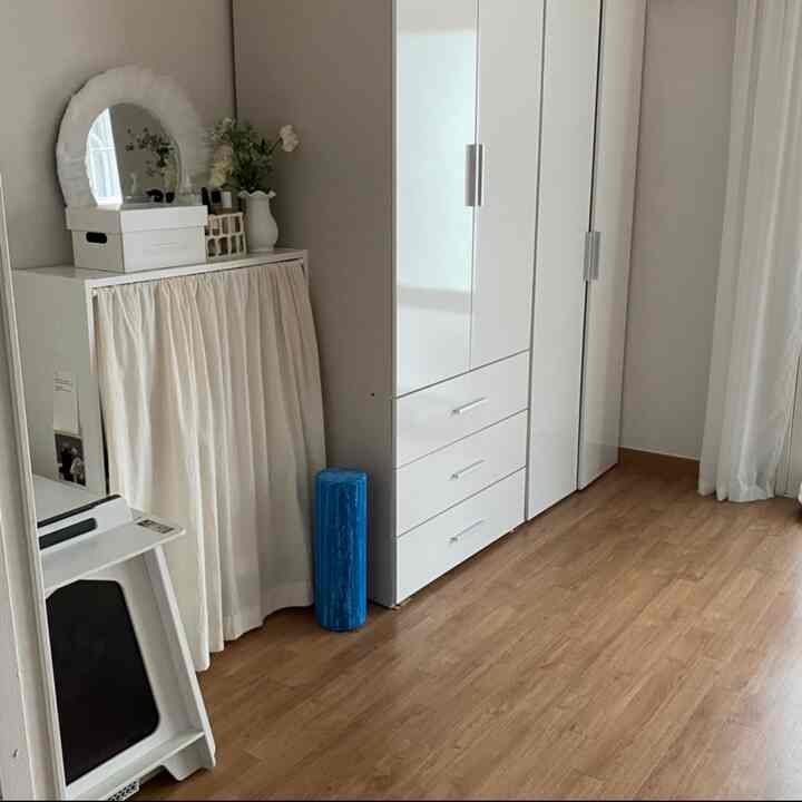 白と木目調のワードローブと棚が配置された整理されたリビングスペースの一角