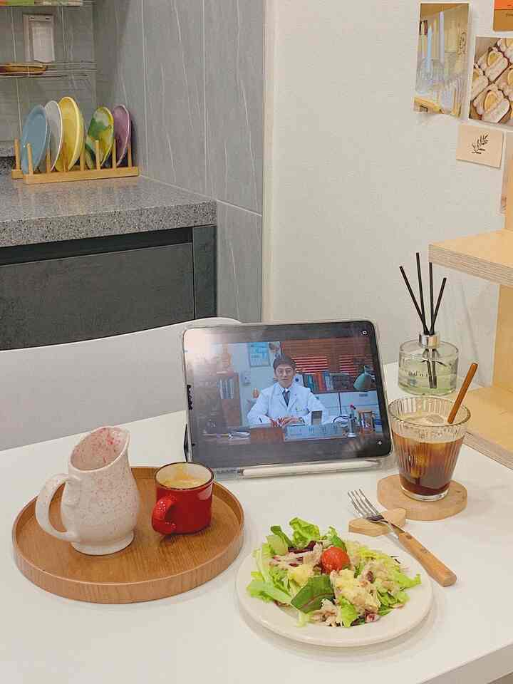 白とナチュラルカラーのキッチンダイニング、テーブル上に多様な食器とディフューザーが配置された雰囲気あるおうちカフェのインテリア