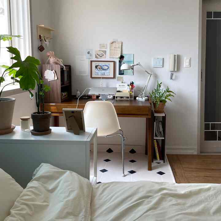 木目調と白を基調としたホームオフィス、机と椅子、植物が配置されたシンプルで居心地の良いインテリア