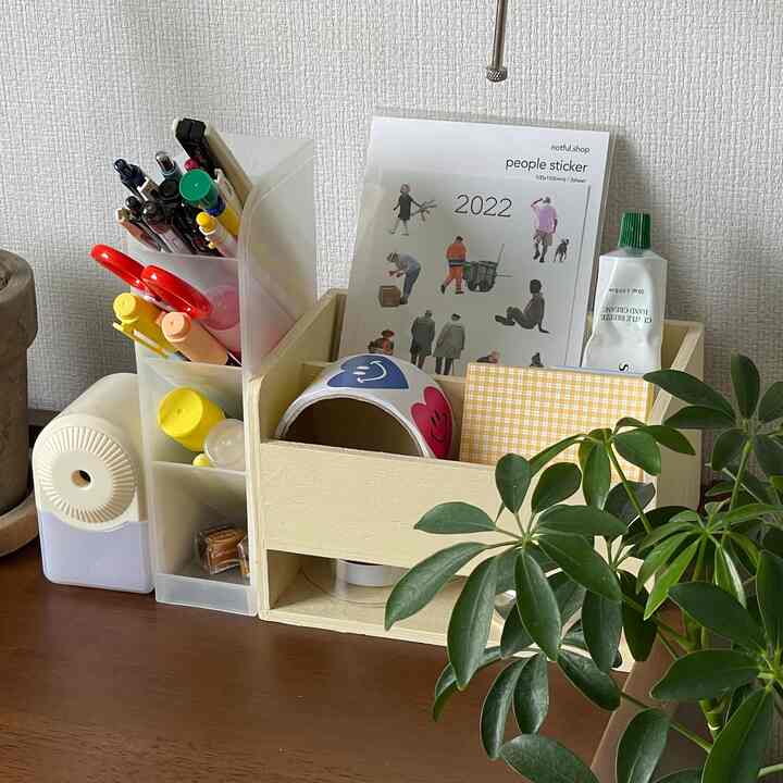 ナチュラルな色調のデスク、ミニ収納ボックスと透明なペン立てに化粧品や文具が整頓された雰囲気のあるインテリア