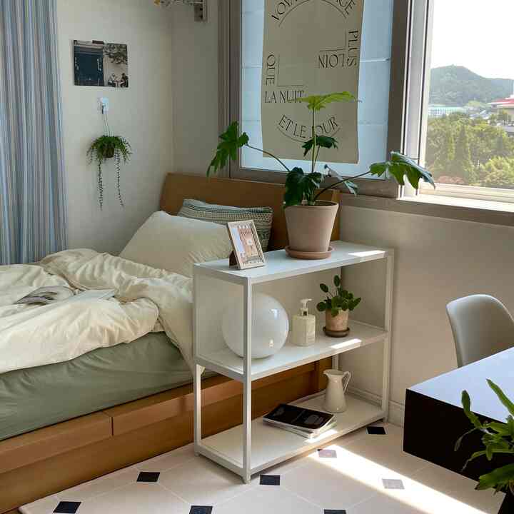 白と木目調が調和する寝室、窓際に置かれた植物と棚が自然な雰囲気を醸し出す落ち着いた空間