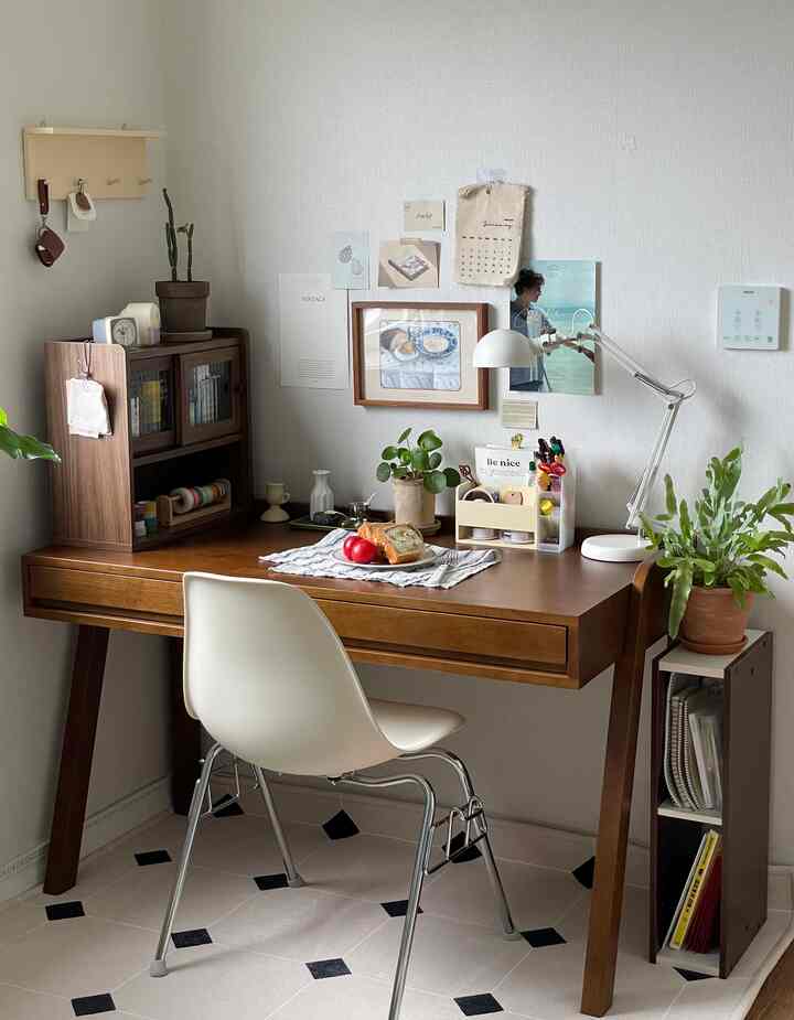 ナチュラルなブラウン色調の書斎兼ホームオフィス空間、木製デスクと白い椅子、デスクライトが配置された落ち着いた雰囲気のインテリア