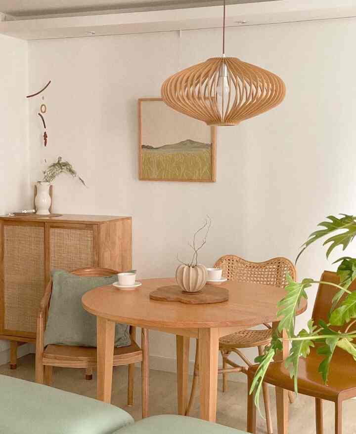 ナチュラルな木目調の壁と天然木の円形ダイニングテーブル、ラタンチェアが配置された温かみのあるダイニング兼ホームオフィス空間
