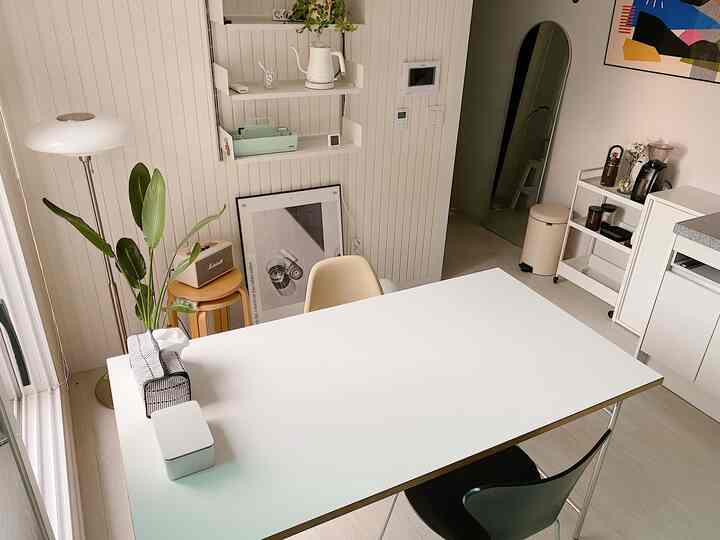 白とベージュの色調のダイニング、清潔感のある白いダイニングテーブルと自然な植物が配置された雰囲気のあるインテリア