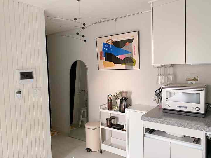 ホワイトとブラックの色調のキッチン空間、モビールと抽象的なポスター、コーヒー器具が配置された清潔感のあるおうちカフェのインテリア