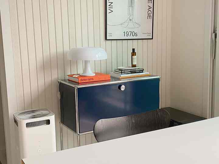 ホワイトとネイビーのトーンでまとめられたミニマルな二人暮らしのリビング、USM収納とアルテミデ・ネッシーノ照明が配置された洗練された空間