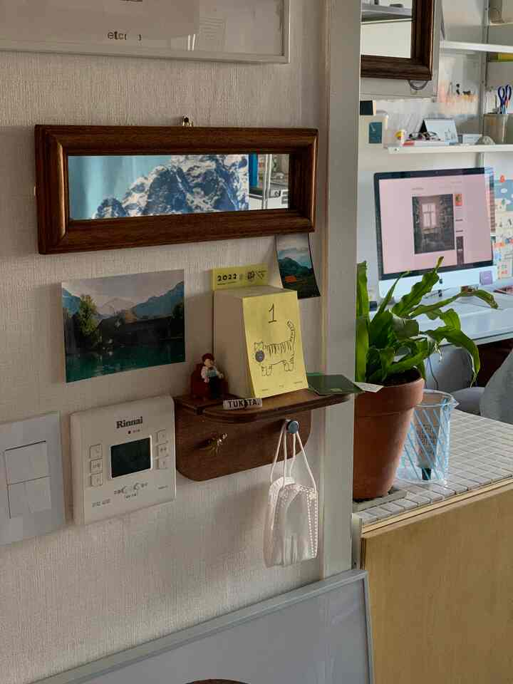 ナチュラルな色調の玄関、木製の棚と壁掛け鏡が配置された落ち着いた印象的な空間