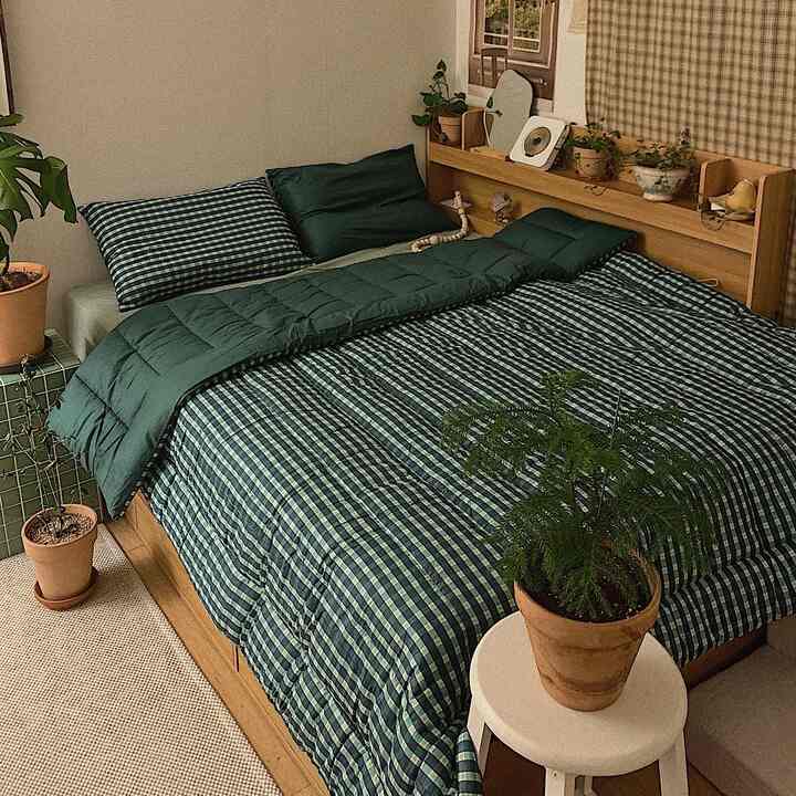 緑の寝具と木目調のベッドが配置された自然を感じる寝室のインテリア