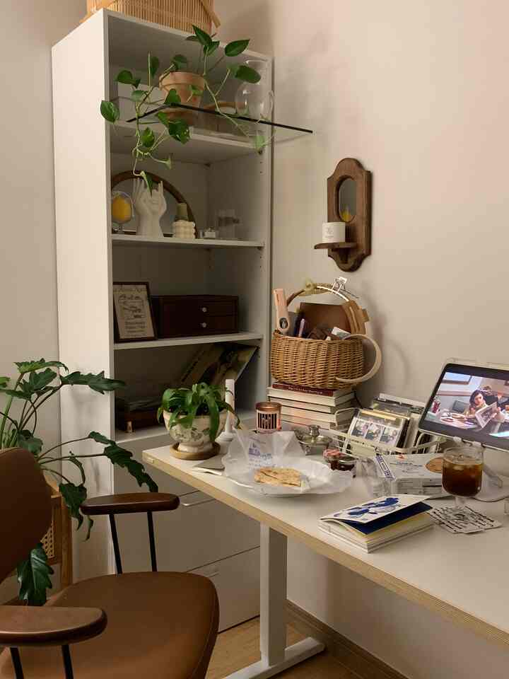 ホワイトとブラウンの色調が特徴のホームオフィス、デスクとオフィスチェア、植物や小物が置かれた雰囲気のある作業空間