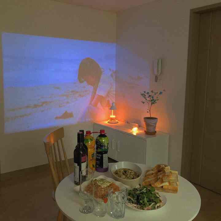 白を基調としたリビングダイニング、丸いテーブルに軽食が並び、温かいキャンドルの照明が雰囲気のあるインテリア