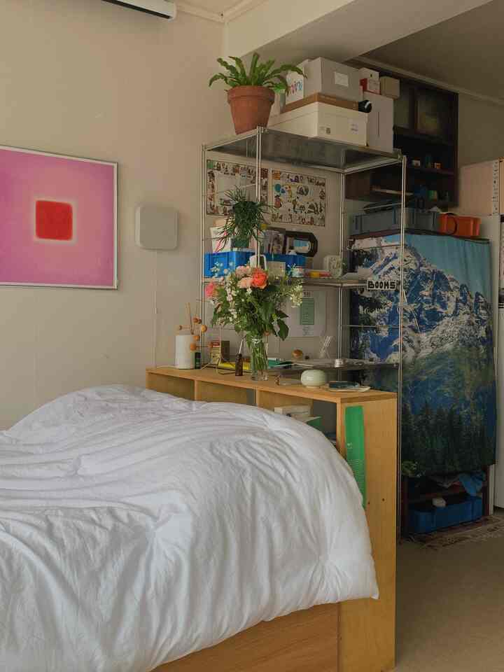 白と木目調の寝室、棚とポスターが配置されて雰囲気のあるインテリア