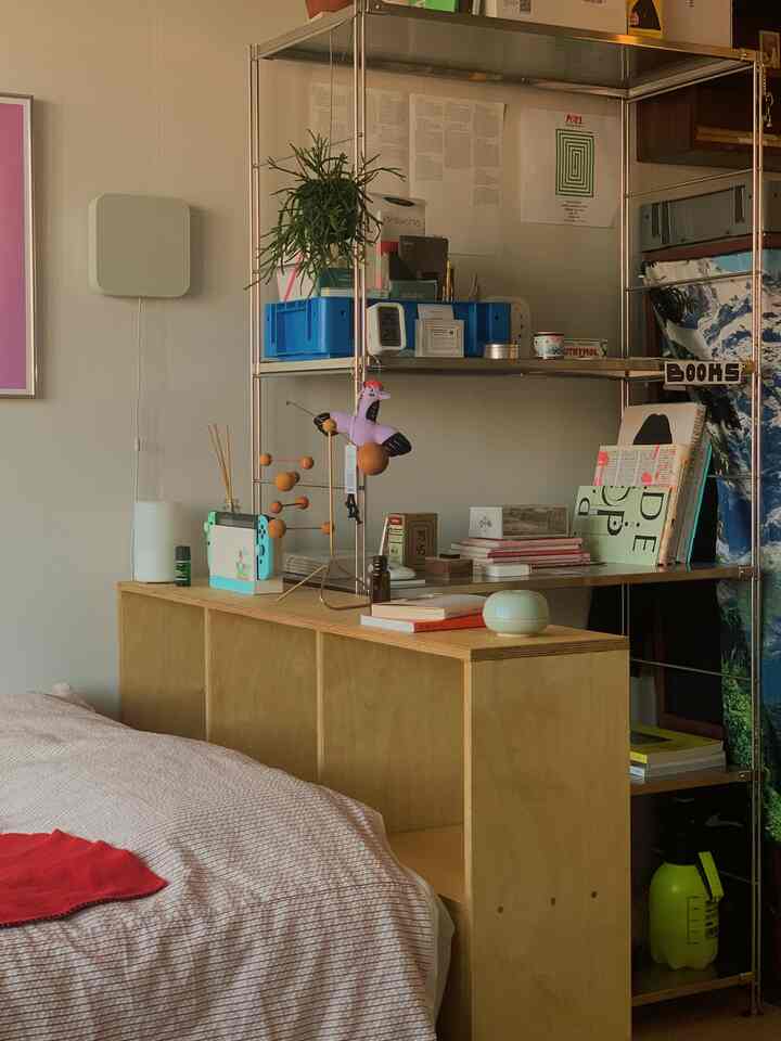 ベージュと木目調が基調の寝室、木製家具と本棚、ディフューザーが配置された落ち着いた印象のインテリア