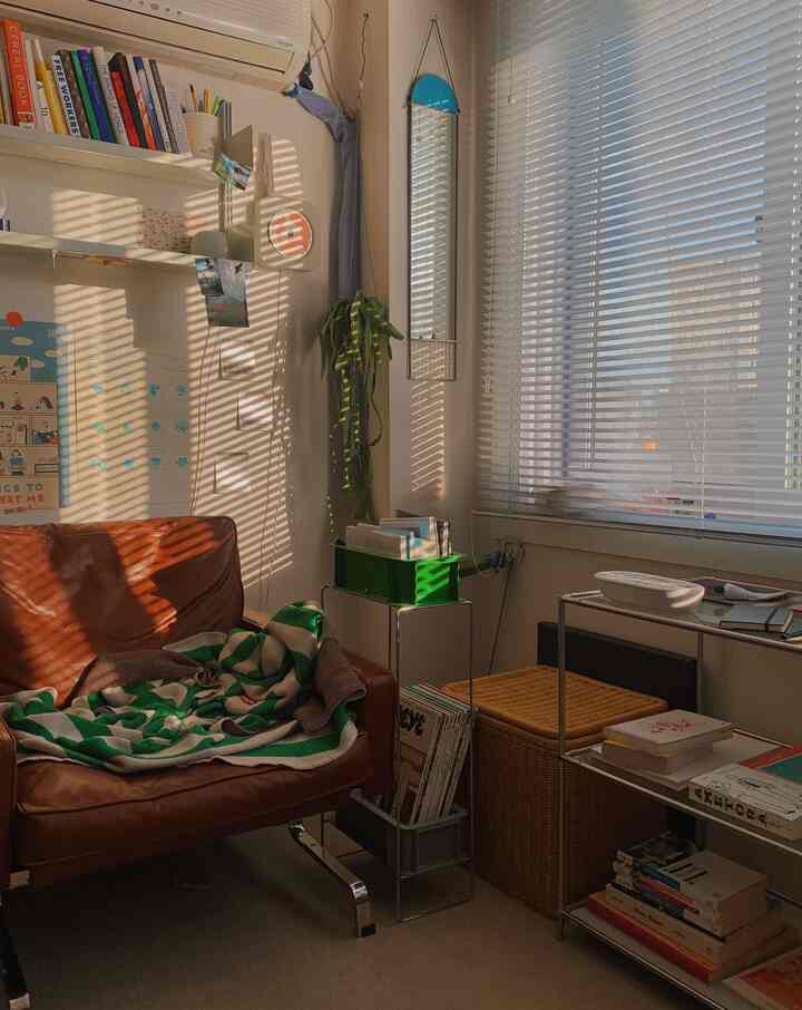 暖かい茶色のソファと白いブラインドがあるワンルームのリビング、居心地の良い個人的な雰囲気のインテリア