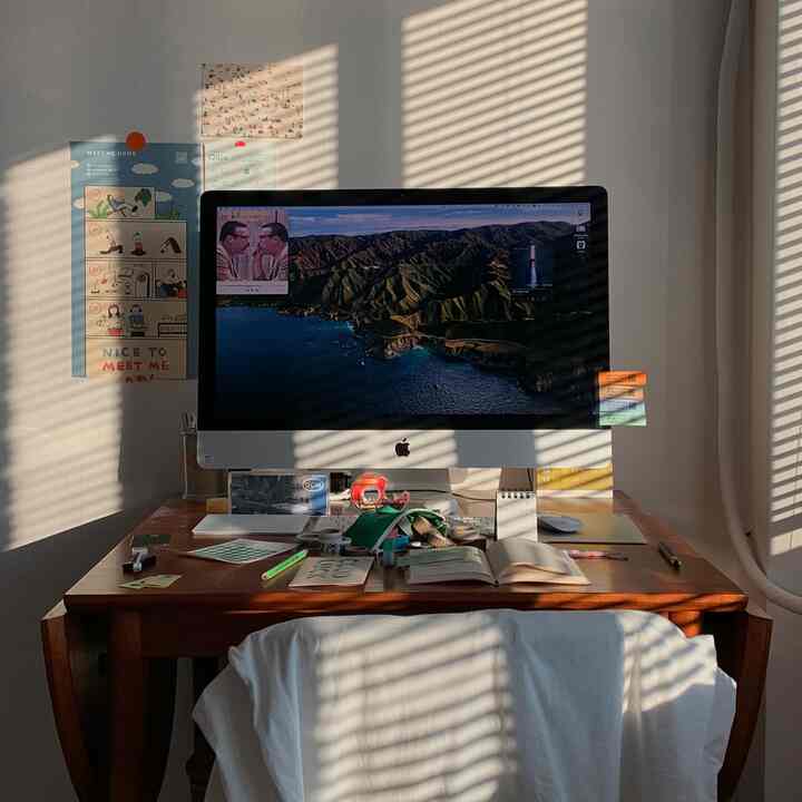 木目調のデスクと白い壁が配されたホームオフィス、午後の日差しが差し込む落ち着いた雰囲気のあるインテリア