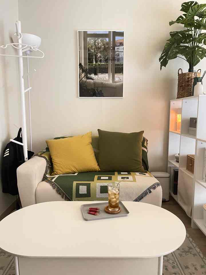 ナチュラルな木目調とホワイトが調和したリビング、柔らかなソファに幾何学模様のブランケットとクッションが配置された雰囲気のある空間