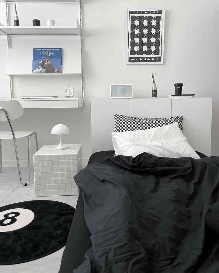 モノトーンの黒白の寝室、シンプルなベッドとデスクが配置された清潔感のある空間