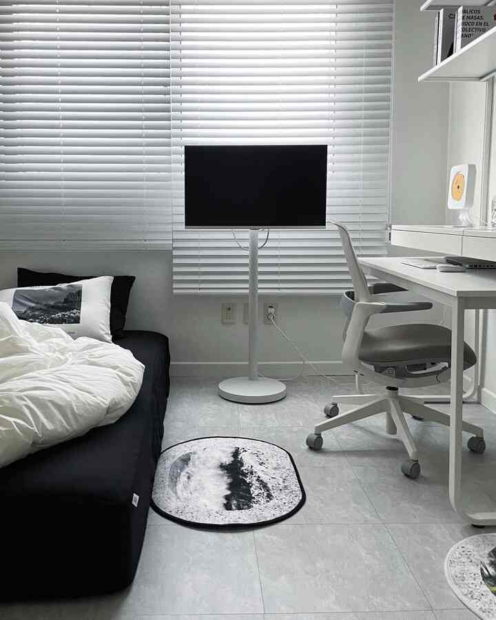 白と黒のトーンのワンルームホームオフィス、ベッドとデスクが調和するシンプルなインテリア