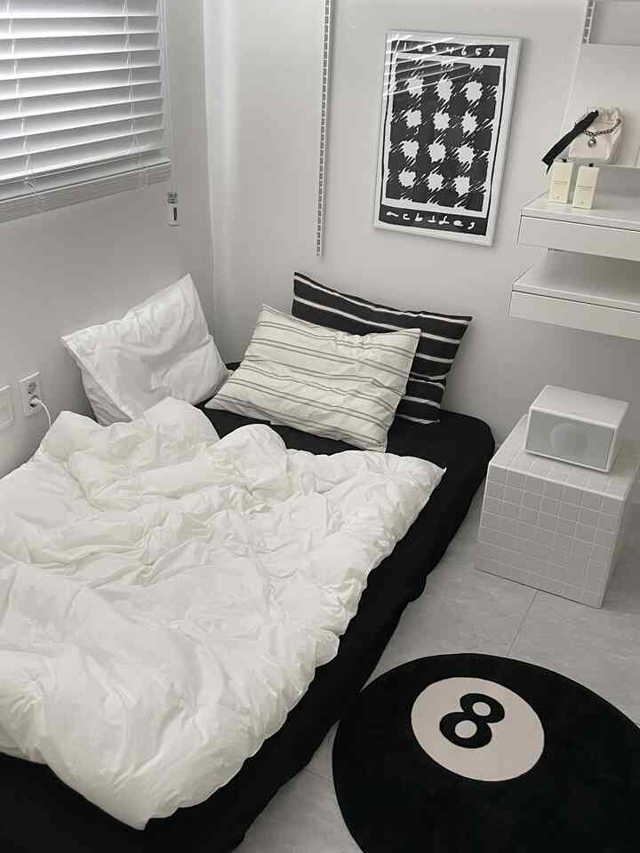 白と黒のトーンの寝室、シングルベッドと8ボール柄のラグが配置されたシンプルでモダンな空間
