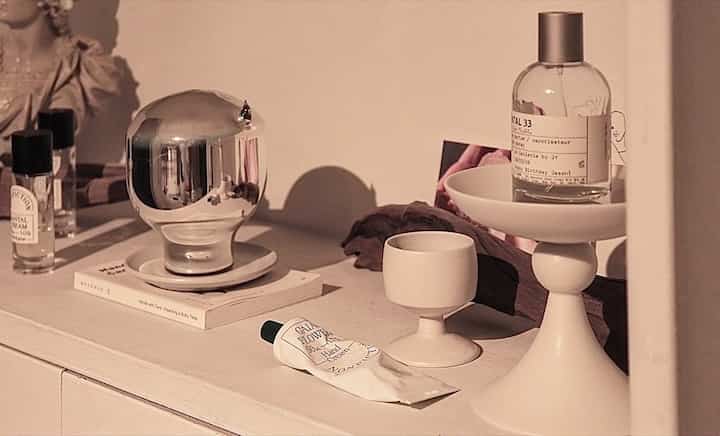 暖かいベージュの色調の空間にホワイトのオブジェやカップ、化粧品が配置された落ち着いたインテリア