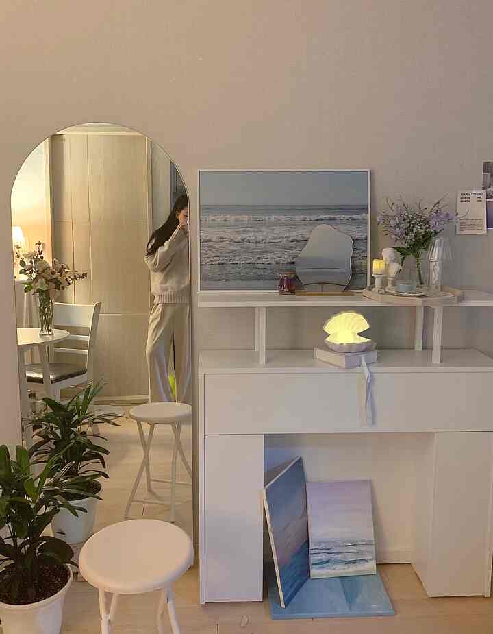 柔らかい白を基調としたおうちカフェ空間、アーチ型の鏡や暖炉コンソール棚、ポスターとムードランプが暖かい雰囲気を演出するインテリア