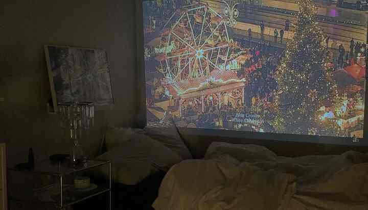 温かみのあるホワイトとブラックの寝室、広い壁に映写機が投影された印象的なホームシネマ空間