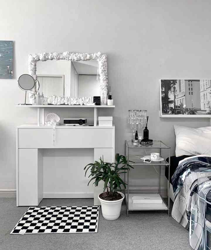 モノトーンでシンプルモダンな寝室、大型の装飾的な鏡と白いコンソール、チェッカーカーペットが配置された印象的な空間