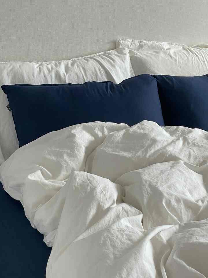 白とネイビーの調和が美しい寝室の寝具セット、落ち着いた清潔感のある空間