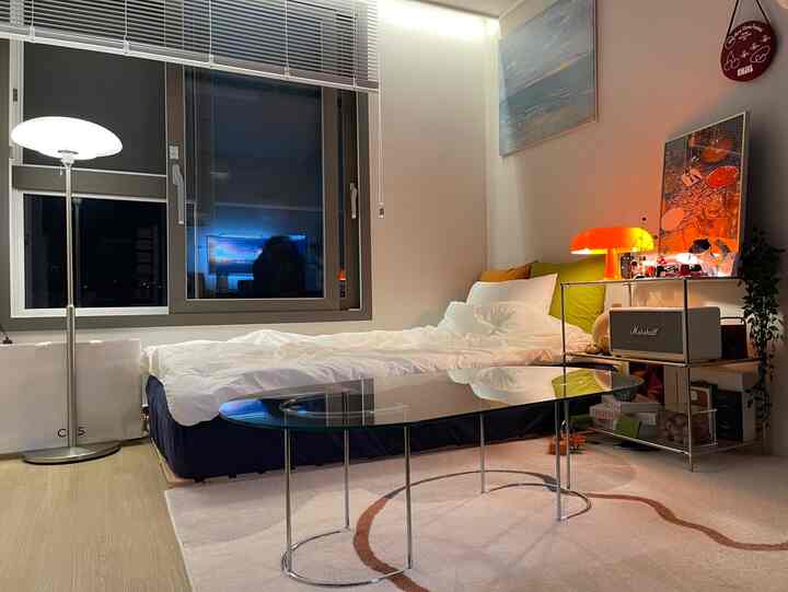 ホワイトとネイビーのトーンのモダンで落ち着いた寝室、ベッド、ナイトテーブル、フロアランプが配置されたインテリア