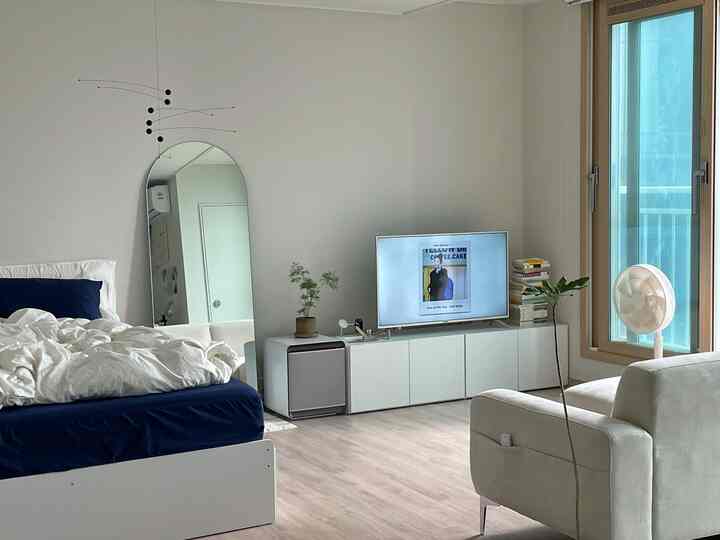 白と青を基調とした寝室とリビング、全身鏡とテレビ台が配置されたモダンで清潔感のあるインテリア