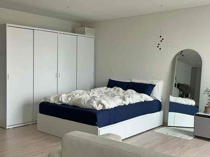 白とネイビーの色調の寝室、クイーンサイズベッドとスライド式クローゼット、全身鏡が配置されたシンプルモダンなインテリア