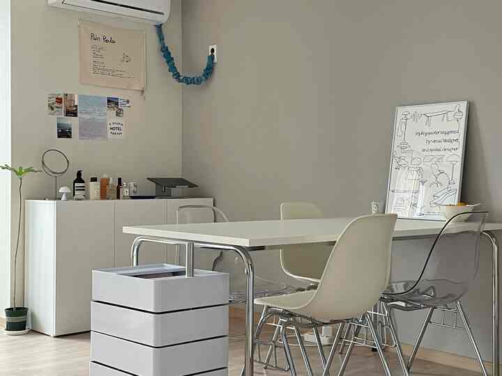 白とグレーのトーンのモダンダイニング、透明な椅子と額縁が配置された雰囲気のある空間