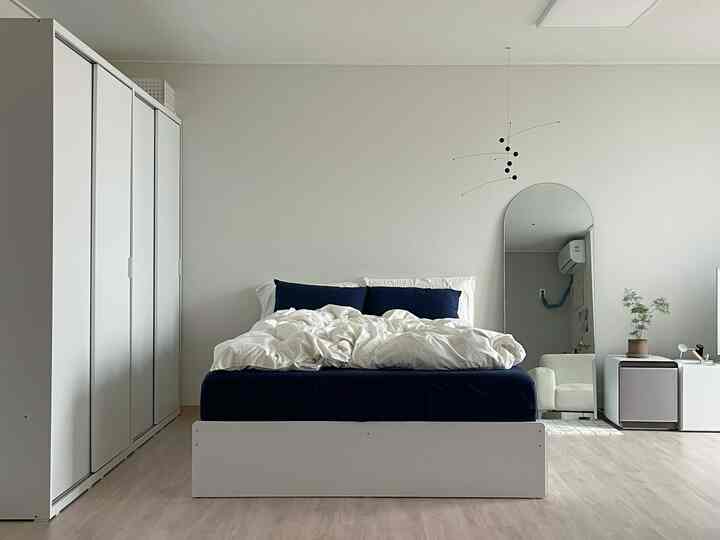 白とネイビートーンの寝室、収納ベッドとスライディングクローゼットが配置されたミニマルなインテリア