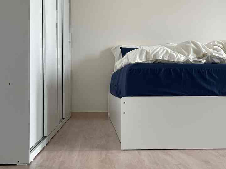 白とネイビーの色調の寝室、スライディングクローゼットと収納ベッドが配置されたシンプルでモダンなインテリア