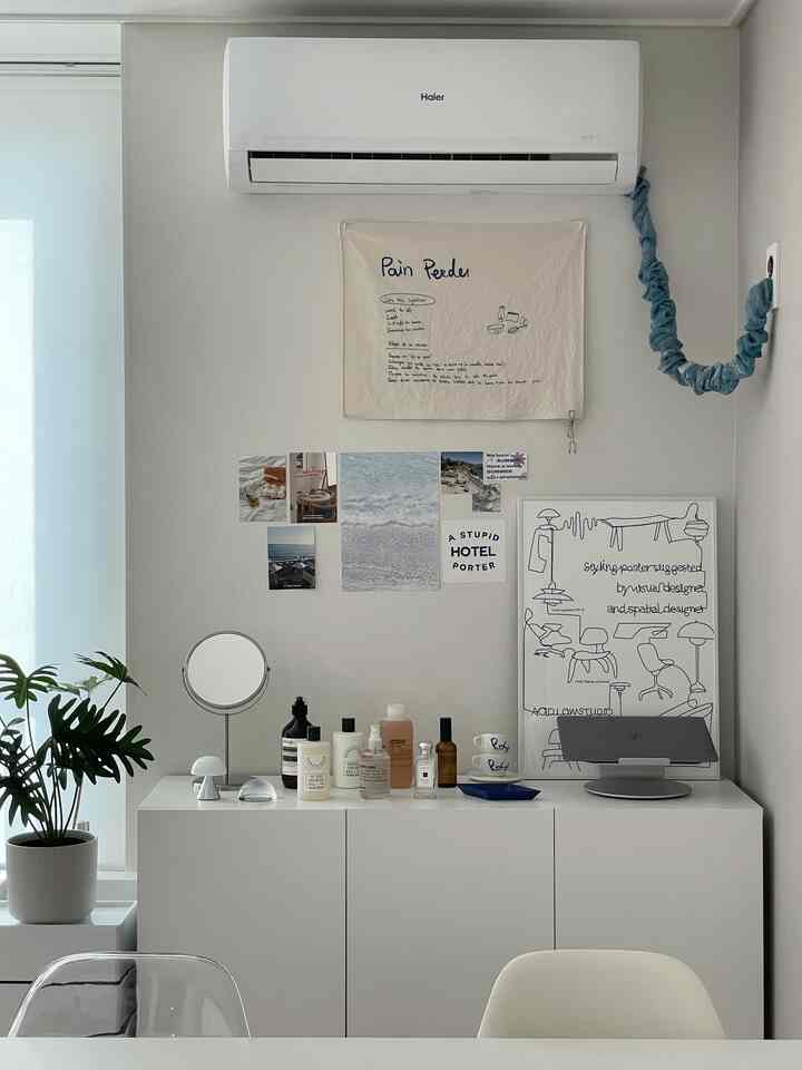 ホワイトと透明感のあるモダンなホームオフィス空間、キャビネットの上には鏡とポスターが配置された清潔感のあるインテリア