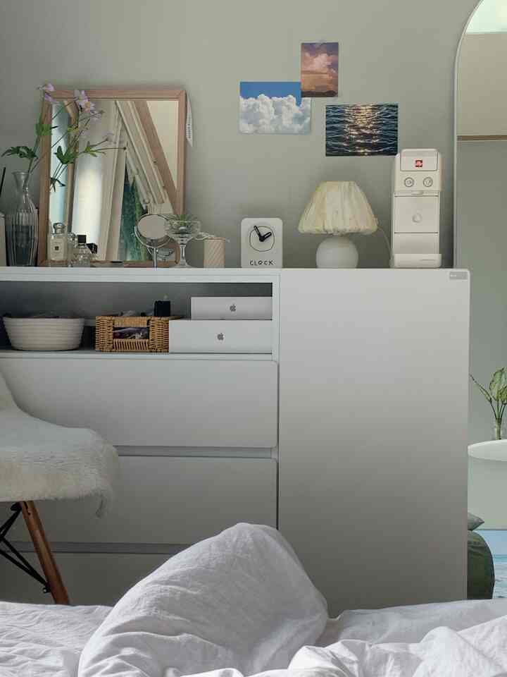 白とナチュラルカラーの寝室、ナイトテーブルと化粧台の鏡、テーブルランプが配置された雰囲気のあるインテリア