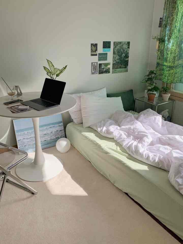白と緑のトーンの狭い一人用寝室、シンプルなレイアウトのデスクとベッド、自然を感じる落ち着いた雰囲気のインテリア