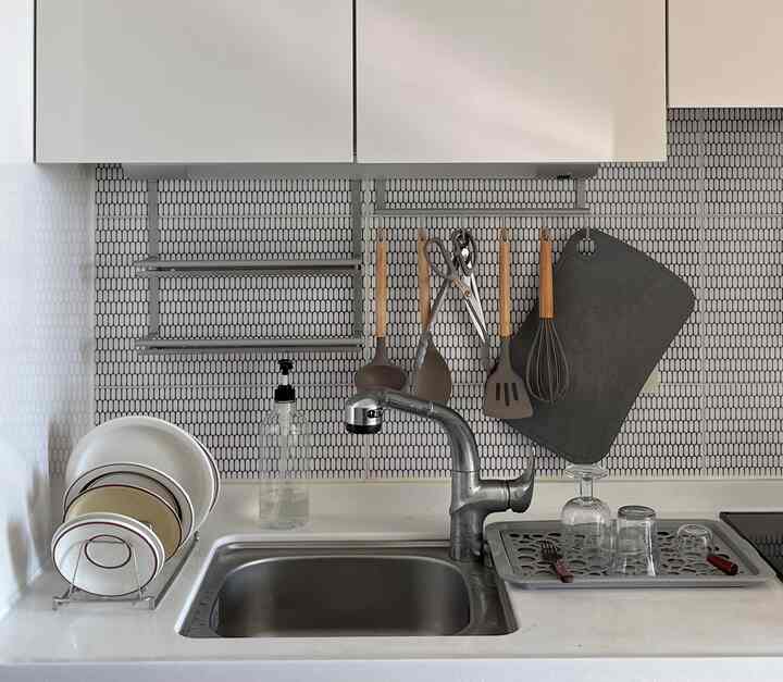 白とグレーの色調のキッチン、シンクや食器乾燥ラックが配置されたミニマルで清潔感のある空間