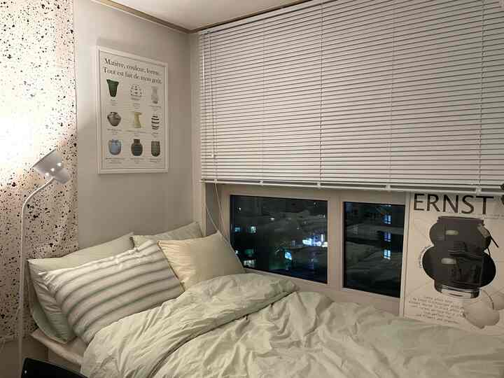 ミント色調の寝室、白いブラインドとシンプルな家具が配置された落ち着いた印象の空間