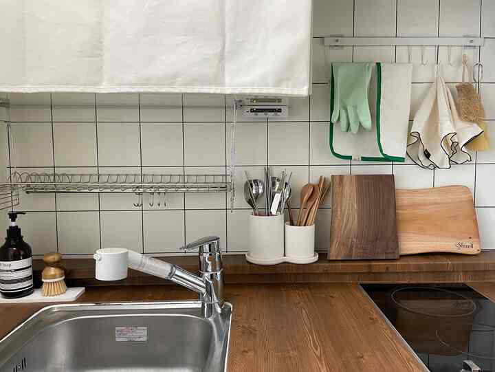 白いタイルと木目調カウンターがある清潔なキッチン、まな板とタオルが自然な雰囲気を演出