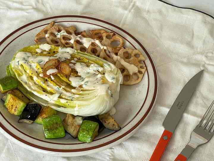 白いリネンの上に茶色の縁の皿とオレンジ色の持ち手のカトラリーが置かれた清潔感のあるダイニングスペース