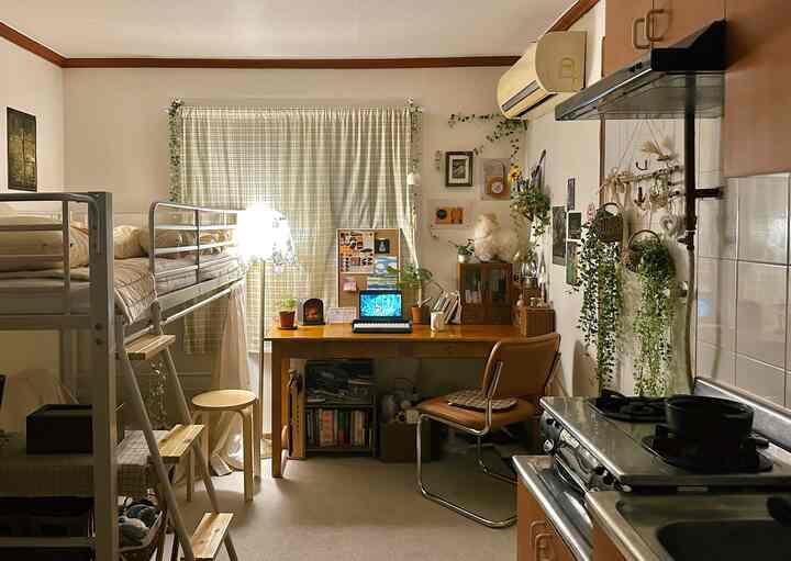 ナチュラルカラーと温かみのある木目調が調和した一人暮らしのホームオフィス空間、高いロフトベッドとかわいらしい小物がある居心地の良い部屋