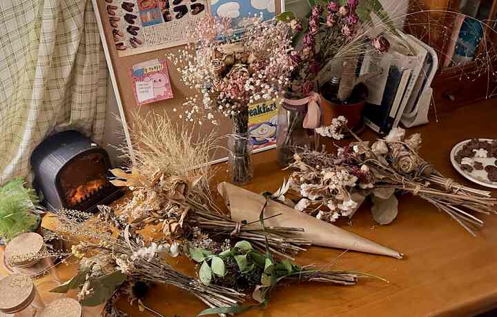 ブラウンとナチュラルな色調のテーブルの上にたくさんのドライフラワーと花瓶が配置された、雰囲気のあるナチュラルなインテリア