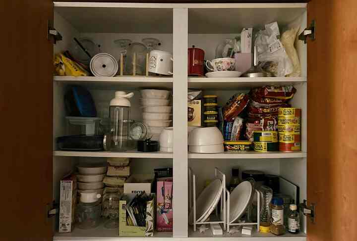 白い棚が設置されたキッチンのパントリーで、皿立てと様々な食器や食品が整然と収納された印象的な空間
