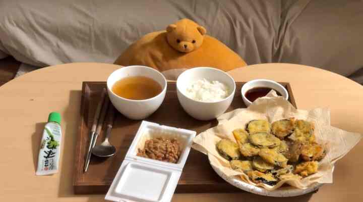 ナチュラルな色調のワンルームに、小さな食卓があり、韓国の食事セットと天ぷらの皿が置かれた雰囲気のあるインテリア